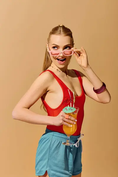 Joven alegre muestra su moda juguetona mientras sorbe una bebida colorida en la relajación. — Stock Photo