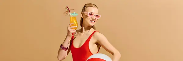 Eine lebhafte junge Frau hält ein buntes Getränk und einen Strandball in der Hand und strahlt in sommerlicher Kleidung Freude aus. — Stockfoto