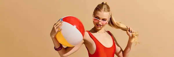 A cheerful young woman in a bright beach setting plays with a beach ball, showing her style. — Stock Photo