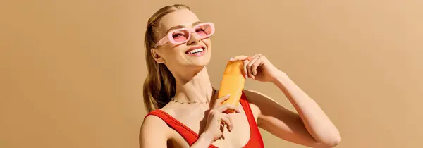 Young woman radiates joy while holding a bright accessory against a warm backdrop of pastel colors — Stock Photo