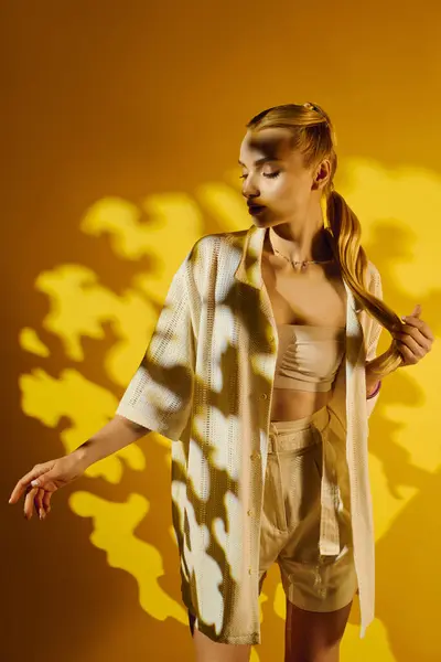 A young woman displays modern fashion, softly engaging with the captivating shadows behind her. — Stock Photo
