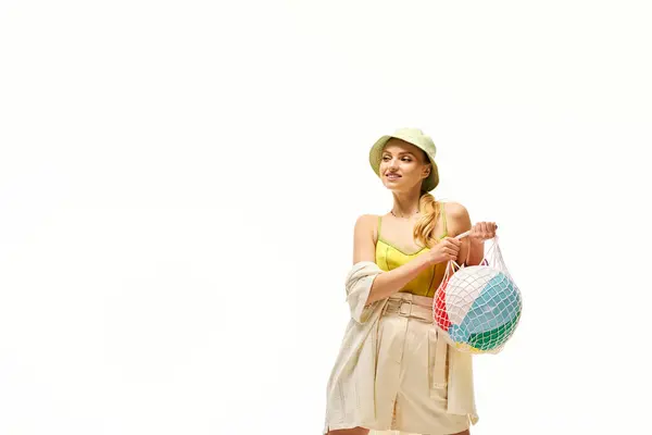 Joyful young woman dressed in stylish summer attire enjoys a playful moment with beach balls. — Stock Photo