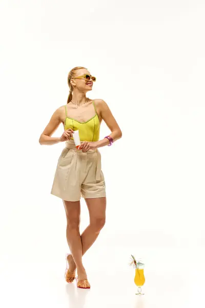 A young woman in a vibrant outfit smiles while holding a drink, radiating joy and confidence. — Stock Photo