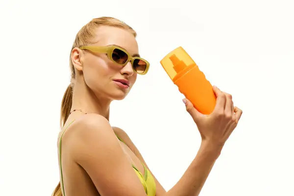 Eine stylische Frau mit Sonnenbrille posiert mit einem leuchtend orangefarbenen Gefäß und strahlt sommerliche Freude aus. — Stockfoto