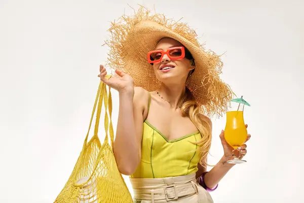A stylish young woman smiles with a colorful drink and bag under her wide brimmed hat. — Stock Photo