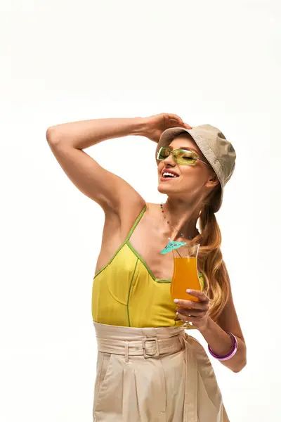 Una giovane bella donna in un abito chic tiene una bevanda vibrante mentre abbraccia le vibrazioni estive. — Foto stock