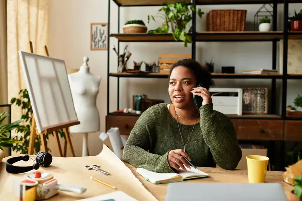 In un vivace laboratorio artigianale, una bella donna parla al telefono mentre prende appunti. — Foto stock