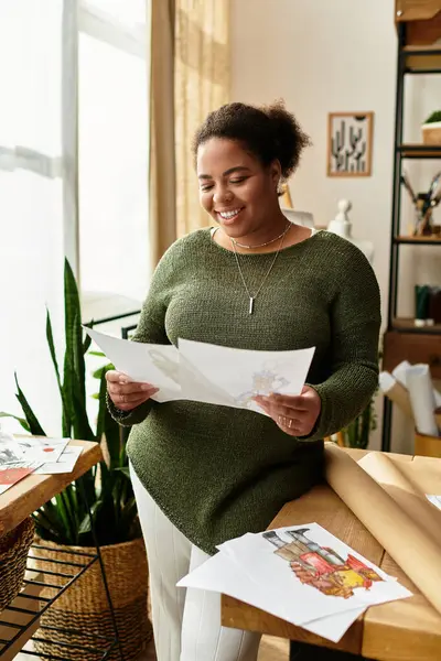 In einem hellen Atelier erkundet eine fröhliche Frau ihre Entwürfe, inspiriert von ihrem kreativen Raum. — Stockfoto