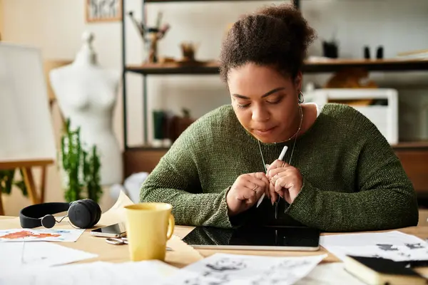 Una hermosa mujer profundamente enfocada en su oficio rodeada de materiales y diseños creativos. - foto de stock