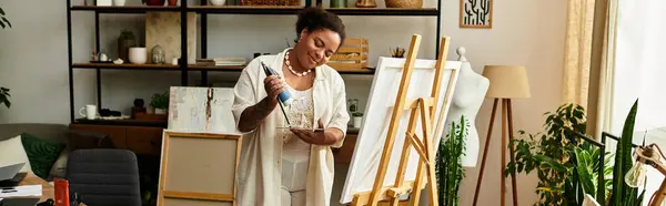 Una hermosa mujer apasionadamente crea arte en un animado taller de artesanía lleno de plantas. - foto de stock