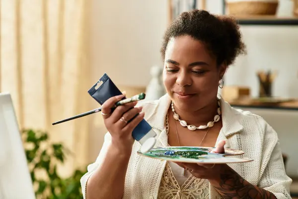 Mujer pinta en una paleta, expresando creatividad en un acogedor espacio de elaboración bien iluminado. - foto de stock