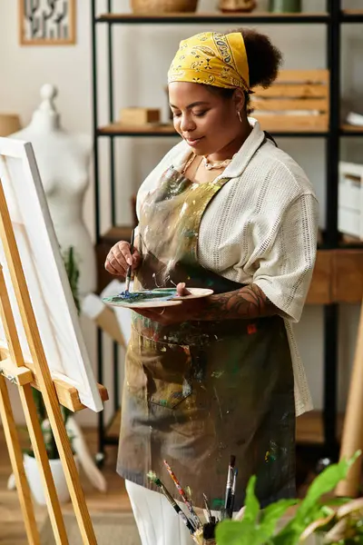 Una hermosa mujer pinta alegremente sobre lienzo, rodeada por un animado ambiente de taller de artesanía. - foto de stock