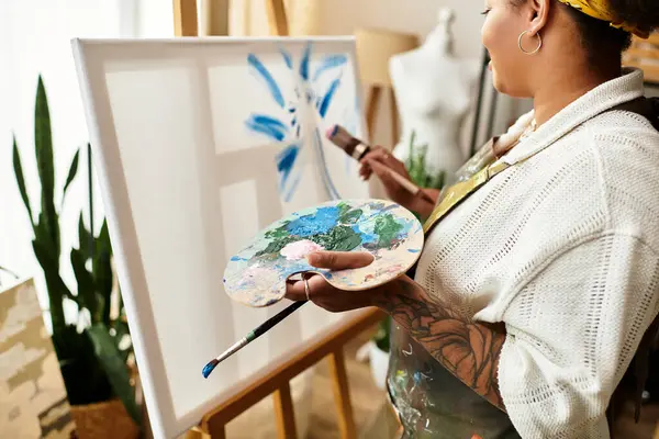In a lively crafting workshop, a woman expresses creativity while painting on a vibrant canvas. — Stock Photo