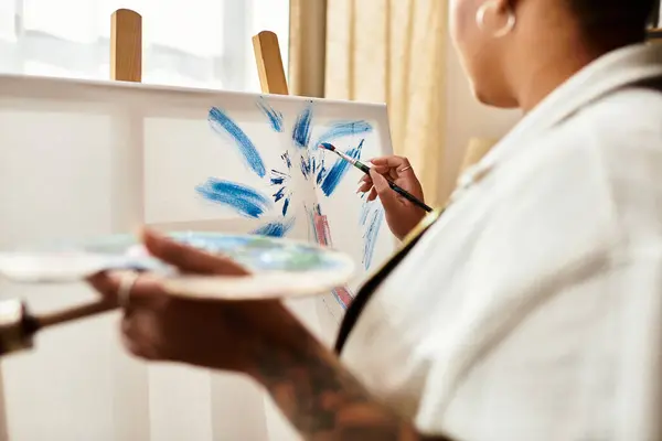 Una hermosa mujer dedicada a la pintura en un taller de artesanía, dando vida a los colores en la lona. - foto de stock