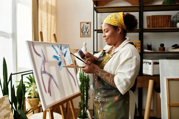 Una donna di talento ornata con una bandana gode di pittura nel suo accogliente laboratorio di artigianato. — Foto stock