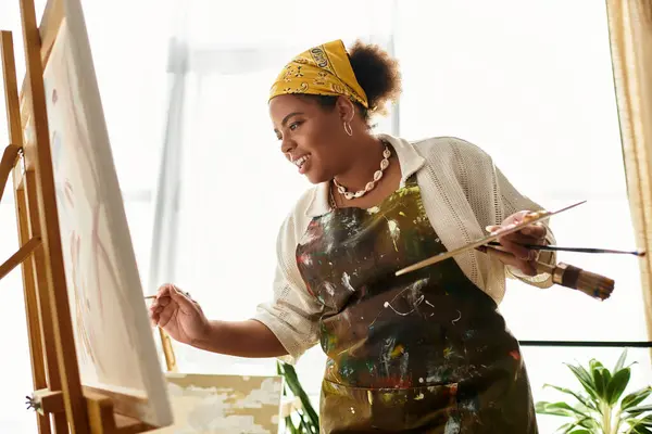 Mujer alegre pinta en un brillante taller, rodeado de arte. - foto de stock