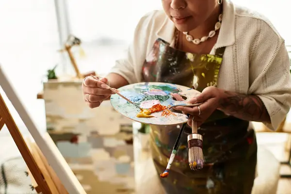 Uma mulher bonita mistura tintas vibrantes em sua oficina de artesanato inspiradora. — Fotografia de Stock