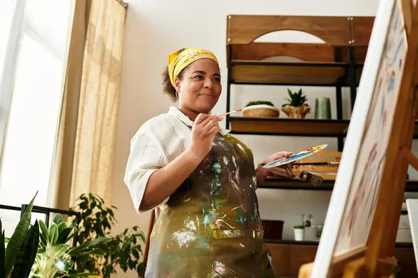 A beautiful woman enjoys her time painting in a lively crafting workshop surrounded by plants. — Stock Photo