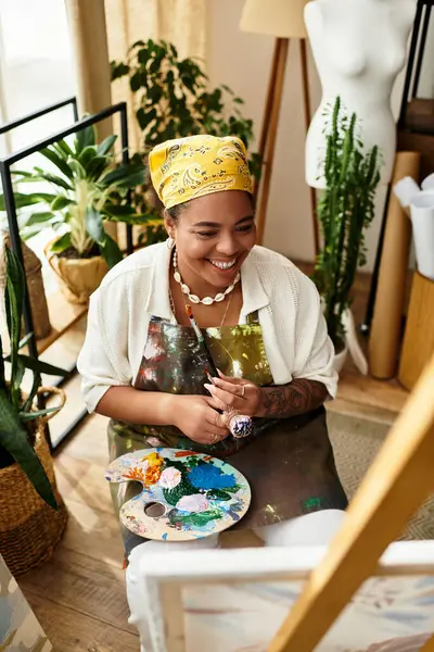 A joyful woman engages in crafting, surrounded by creative tools and plants in a bright workshop. — Stock Photo