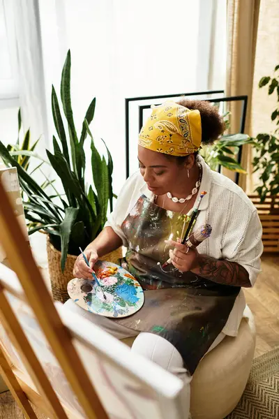 A talented woman engages in vibrant crafting amid lush greenery and sunlight in her workshop. — Stock Photo
