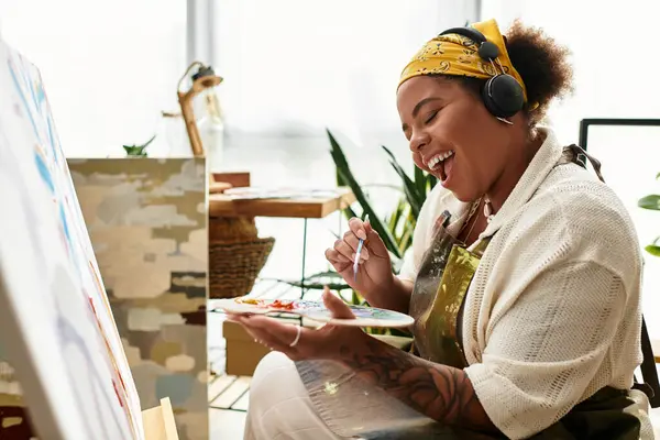 Mujer entusiasta pinta de alegría en un animado taller de artesanía lleno de inspiración. - foto de stock