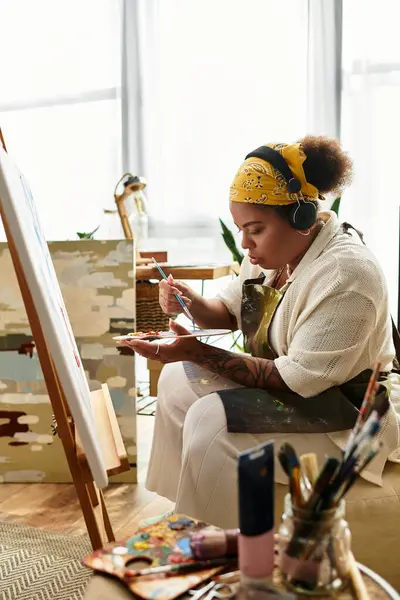 A woman joyfully crafts in a workshop filled with art supplies and bright light. — Stock Photo