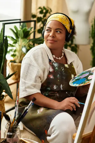 A beautiful woman enjoys a colorful crafting session, surrounded by plants and art supplies. — Stock Photo