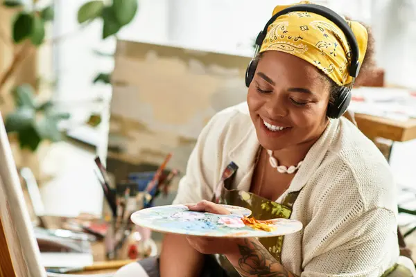 Un'artista esperta mescola colori vivaci su una tavolozza, sorridendo con gioia alla sua creazione artistica.. — Foto stock