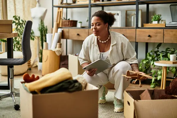 A beautiful woman kneels to organize craft materials in a vibrant and inspiring workshop. — Stock Photo