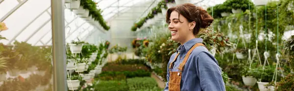 Une jeune femme au pouce vert nourrit des plantes dans un environnement de serre prospère, bannière — Photo de stock
