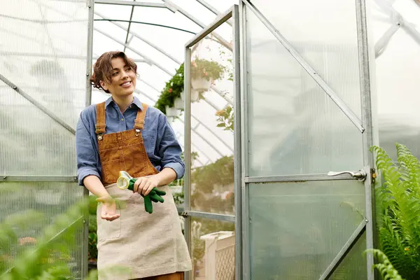 A dedicated gardener tends to flourishing plants inside her serene greenhouse filled with life. — Stock Photo