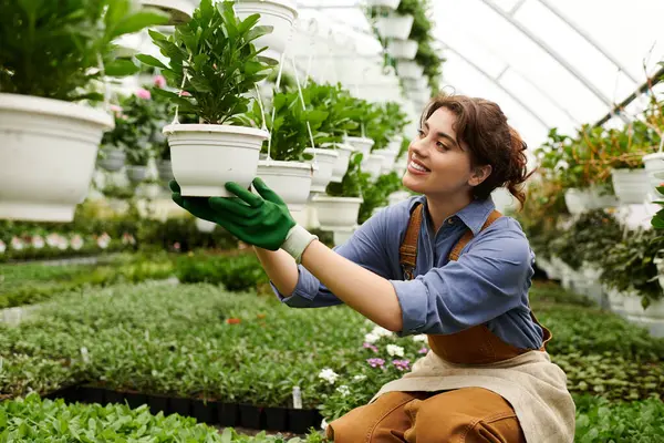 A young woman tends to her flourishing plants inside an inviting greenhouse filled with greenery. — Stock Photo