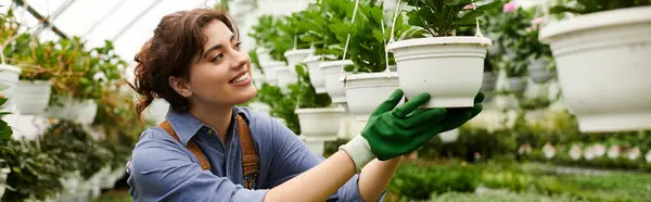 A young woman tends to her flourishing plants in a lively greenhouse, banner — Stock Photo
