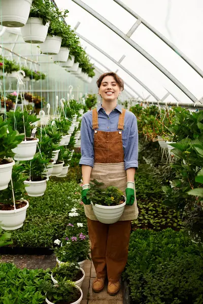 Jovem tende a florescer plantas enquanto desfruta de seu tempo na estufa. — Fotografia de Stock