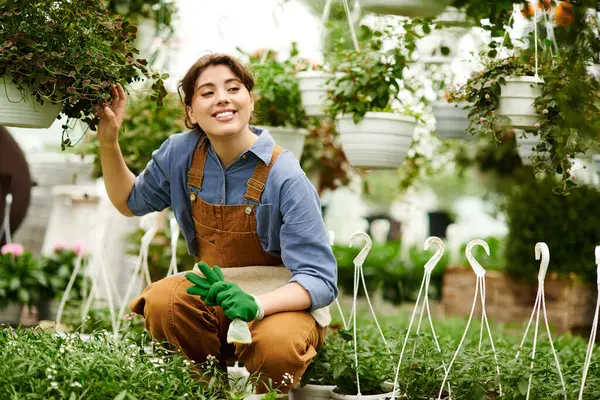 In a peaceful greenhouse, a young woman tends to her flourishing plants with joy and care. — Stock Photo
