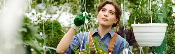 Jeune femme tendant joyeusement des plantes colorées dans une serre ensoleillée, bannière — Photo de stock