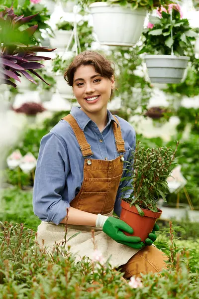 A cheerful gardener tends to potted plants in a lively greenhouse, showcasing her passion. — Stock Photo
