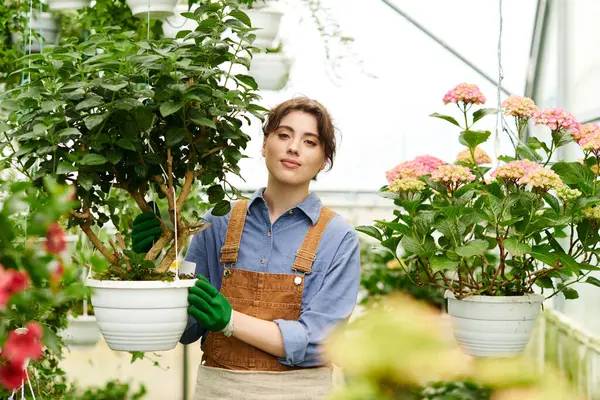 Inside a bright greenhouse, a young woman tends to lush plants, radiating joy and care. — Stock Photo