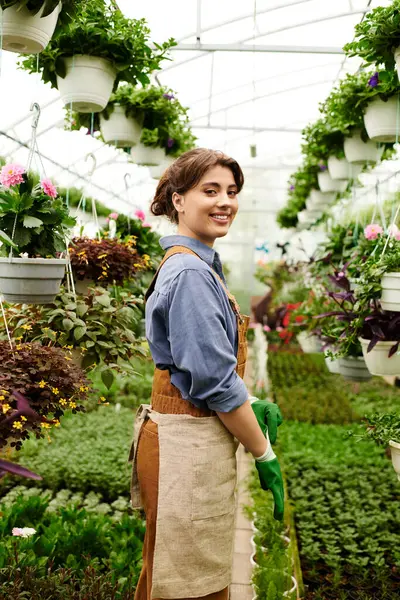 A young woman nurtures lush plants in her greenhouse, showing her love for gardening. — Stock Photo