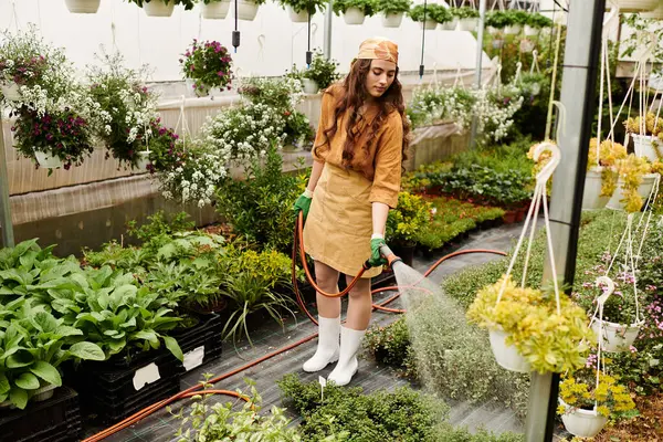 A happy gardener tends to thriving plants in a bright greenhouse, showing her love for nature. — Stock Photo