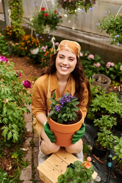 A beautiful young gardener embraces her passion as she nurtures blooming plants in a greenhouse. — Stock Photo