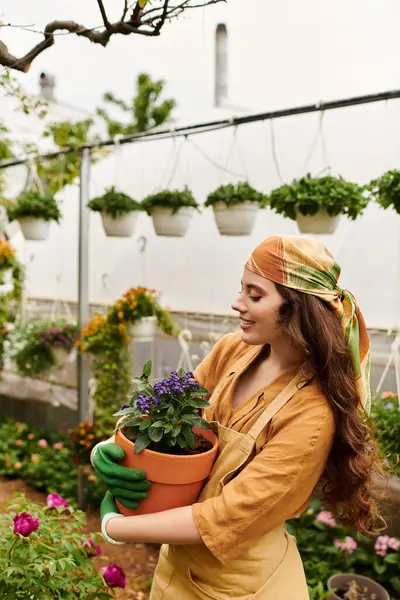 Femme en foulard et tablier tend à planter dans une serre vibrante. — Photo de stock