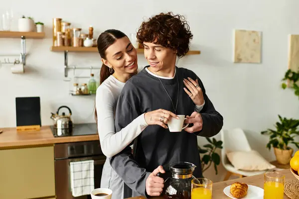 A loving couple shares a tender moment as they prepare coffee in their modern kitchen at home. — Stock Photo