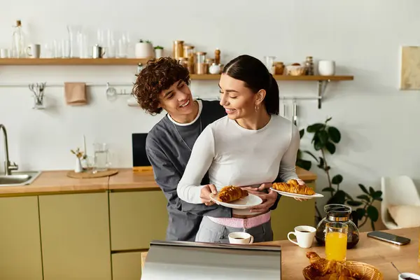 A joyful couple enjoys breakfast in their stylish home, sharing smiles and delicious pastries. — Stock Photo