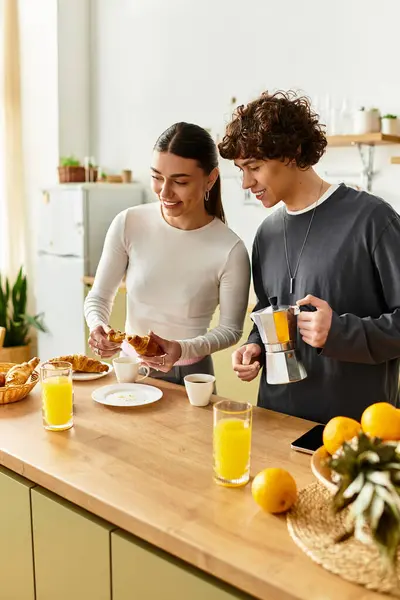 A joyful couple enjoys breakfast together, smiling and savoring pastries in their bright kitchen. — Stock Photo