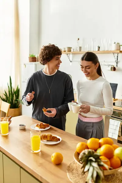 Un hombre y una mujer comparten la risa mientras preparan el desayuno en su hogar luminoso, irradiando amor. - foto de stock