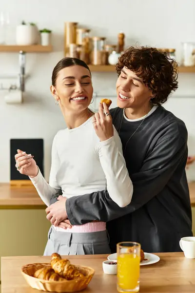 Um homem e uma mulher interagem alegremente em sua cozinha acolhedora enquanto desfrutam do café da manhã, cheio de amor. — Fotografia de Stock