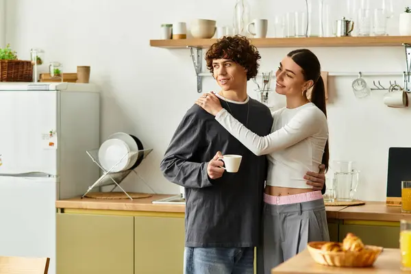 Couple enjoying warm embraces while sharing a cup of coffee in their inviting kitchen space — Stock Photo