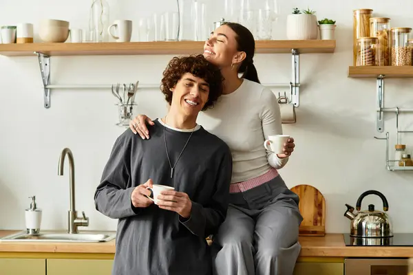 A happy couple enjoys quality time in their kitchen, sharing smiles and laughter with cups in hand. — Stock Photo