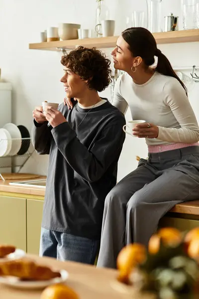 A couple relaxes together in their kitchen, savoring warm drinks and each others company. — Stock Photo